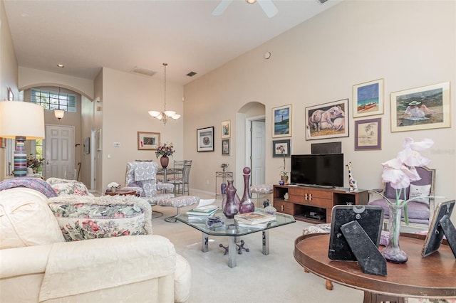 living room with carpet flooring, a high ceiling, and ceiling fan with notable chandelier