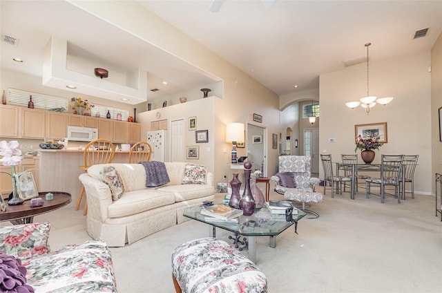 carpeted living room featuring a notable chandelier and a high ceiling