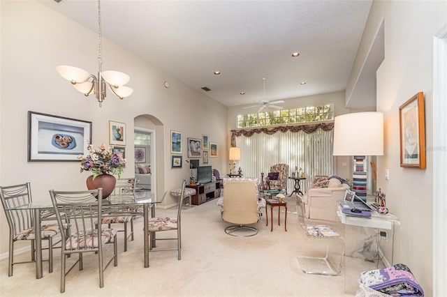 dining room featuring carpet, ceiling fan with notable chandelier, and a high ceiling