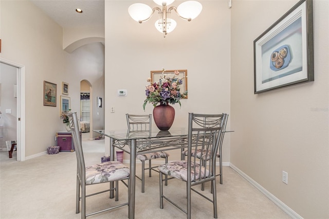 dining space with light carpet and a chandelier