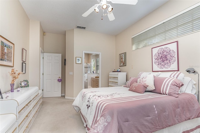 carpeted bedroom with a textured ceiling, ensuite bathroom, and ceiling fan