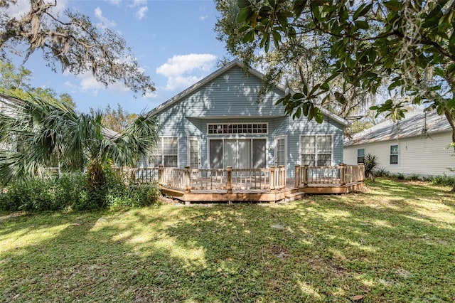 rear view of house featuring a wooden deck and a lawn