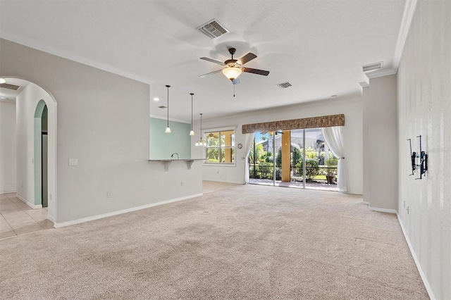 unfurnished living room featuring ceiling fan, ornamental molding, and light carpet