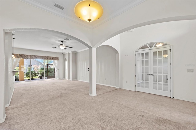 empty room with ceiling fan, crown molding, light carpet, and french doors