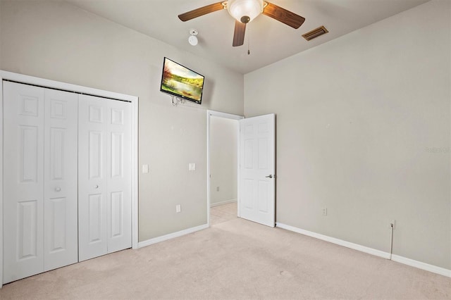 unfurnished bedroom with a closet, light colored carpet, and ceiling fan