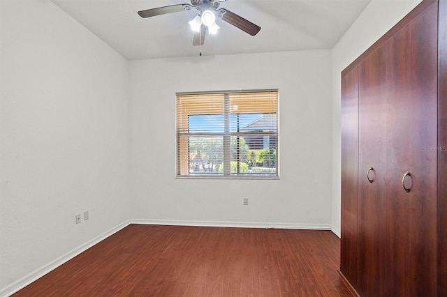 unfurnished bedroom with ceiling fan and dark wood-type flooring