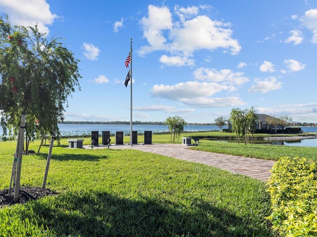 surrounding community with a water view and a yard