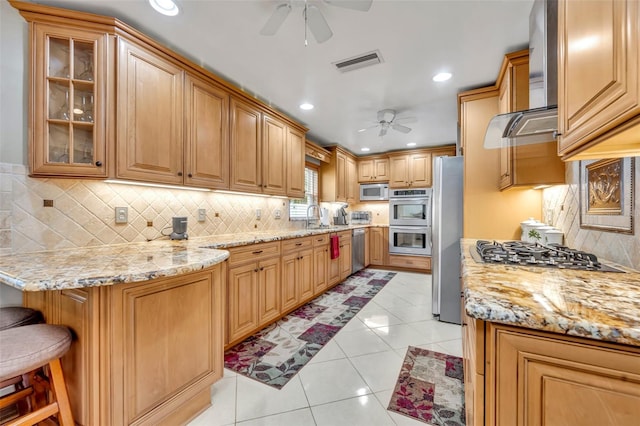 kitchen with ceiling fan, stainless steel appliances, backsplash, a kitchen bar, and light tile patterned floors