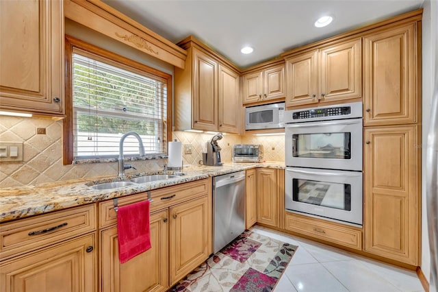 kitchen with appliances with stainless steel finishes, backsplash, light tile patterned floors, and sink