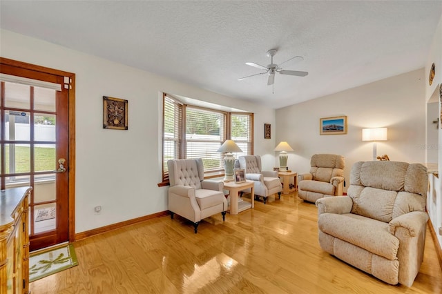 living room featuring ceiling fan, light hardwood / wood-style floors, and a textured ceiling