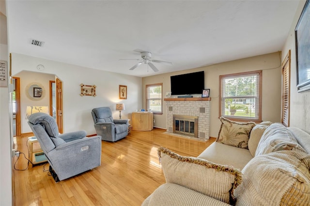 living room featuring a fireplace, hardwood / wood-style flooring, ceiling fan, and a healthy amount of sunlight