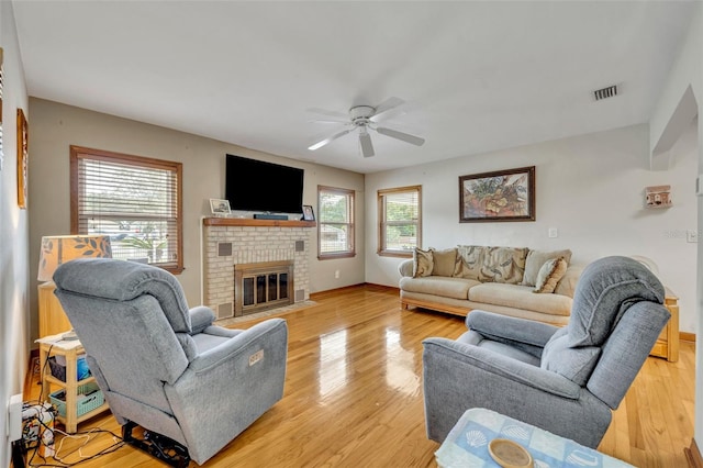 living room featuring ceiling fan, light hardwood / wood-style floors, a fireplace, and a wealth of natural light