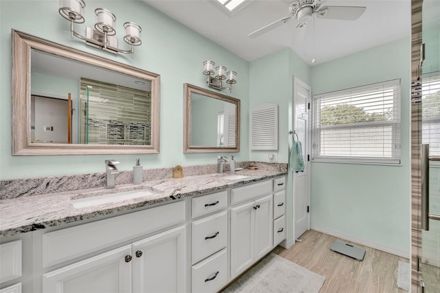 bathroom featuring a skylight, ceiling fan, walk in shower, hardwood / wood-style floors, and vanity