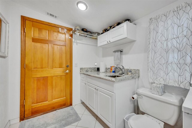 kitchen with white cabinets, light stone counters, light tile patterned flooring, and sink