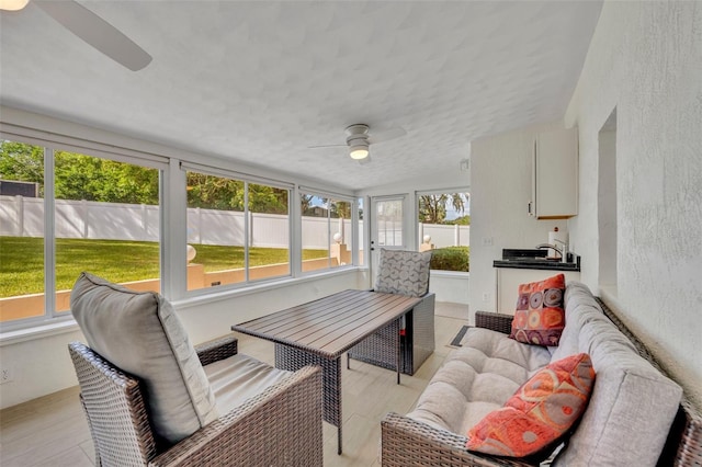 sunroom with sink, plenty of natural light, lofted ceiling, and ceiling fan