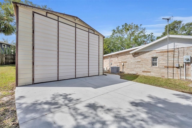 view of outbuilding featuring fence and central AC unit