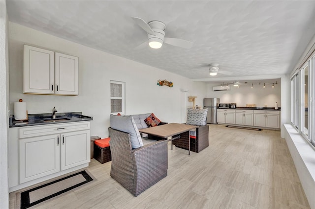 kitchen with a sink, a ceiling fan, an AC wall unit, freestanding refrigerator, and dark countertops