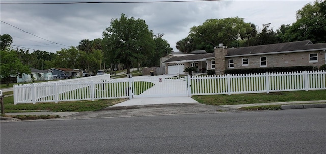 ranch-style home featuring a fenced front yard, a gate, driveway, and a chimney