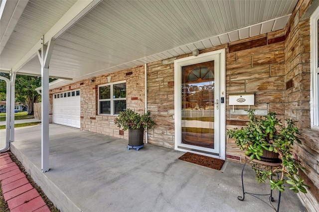 doorway to property featuring a garage, stone siding, and covered porch