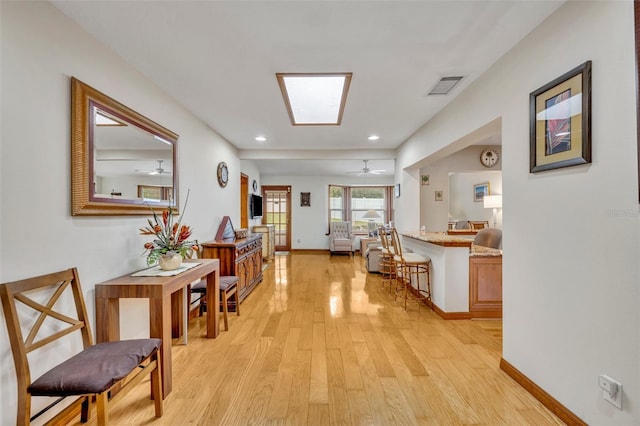 hallway featuring a skylight, recessed lighting, visible vents, light wood-type flooring, and baseboards