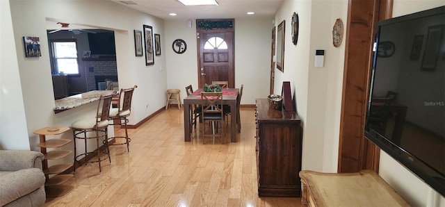 dining room with a fireplace, recessed lighting, a ceiling fan, light wood-type flooring, and baseboards