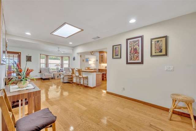 living area with light wood-style floors, baseboards, a skylight, and recessed lighting