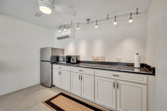 kitchen with a ceiling fan, a wall mounted air conditioner, rail lighting, stainless steel appliances, and light wood-type flooring