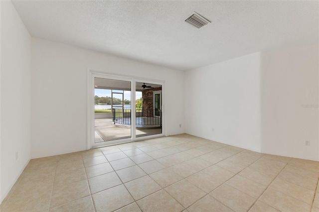 empty room with a textured ceiling and light tile patterned floors