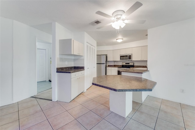 kitchen featuring stainless steel appliances, a kitchen bar, white cabinets, and light tile patterned floors