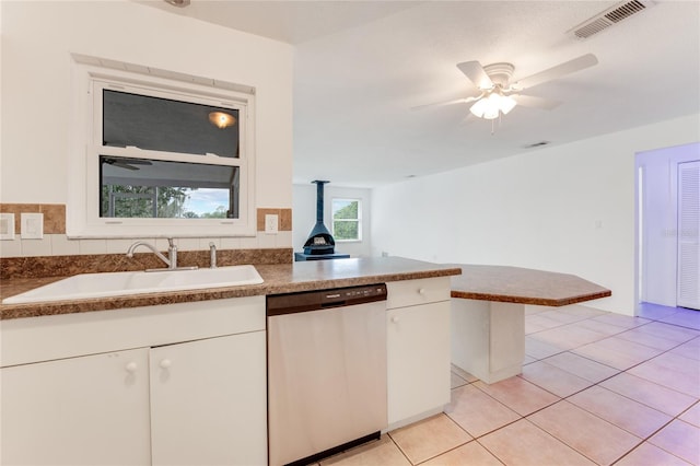 kitchen with dishwasher, kitchen peninsula, white cabinets, sink, and light tile patterned floors