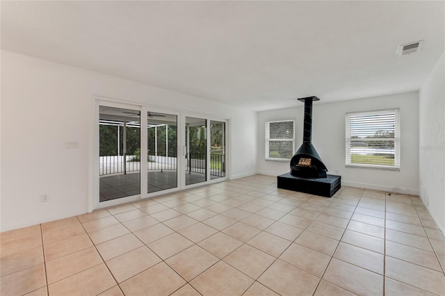 unfurnished living room with light tile patterned floors and a wood stove