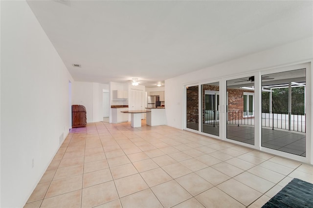 unfurnished living room with light tile patterned floors and ceiling fan