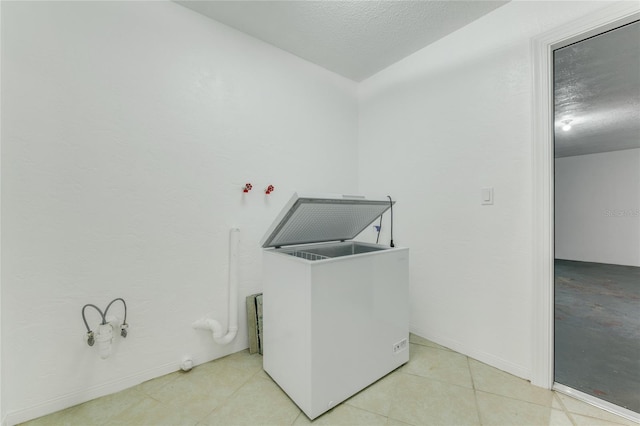 laundry room with a textured ceiling and light tile patterned floors