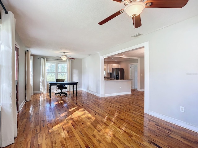 unfurnished living room with ceiling fan, hardwood / wood-style flooring, and a textured ceiling