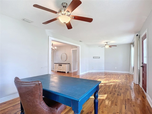 interior space featuring ceiling fan with notable chandelier and hardwood / wood-style floors