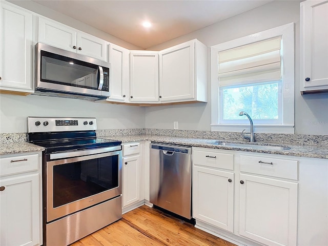 kitchen with sink, white cabinetry, stainless steel appliances, and light hardwood / wood-style floors