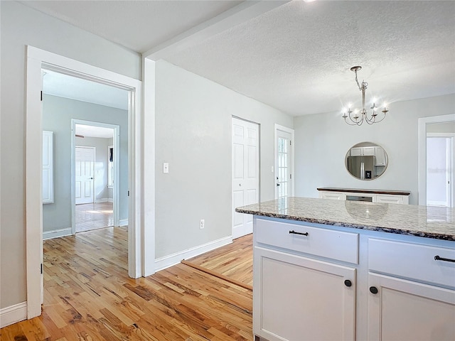 kitchen with white cabinetry, light wood-type flooring, a textured ceiling, and pendant lighting