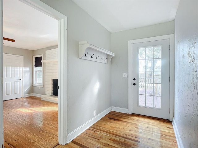 doorway to outside featuring a wealth of natural light, a brick fireplace, and wood-type flooring