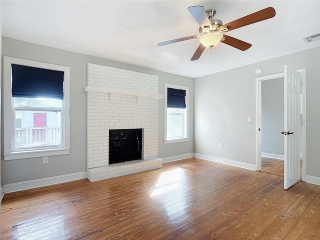 unfurnished living room with hardwood / wood-style floors, a brick fireplace, and ceiling fan