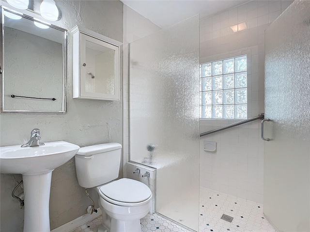 bathroom featuring tiled shower, sink, toilet, and tile patterned floors