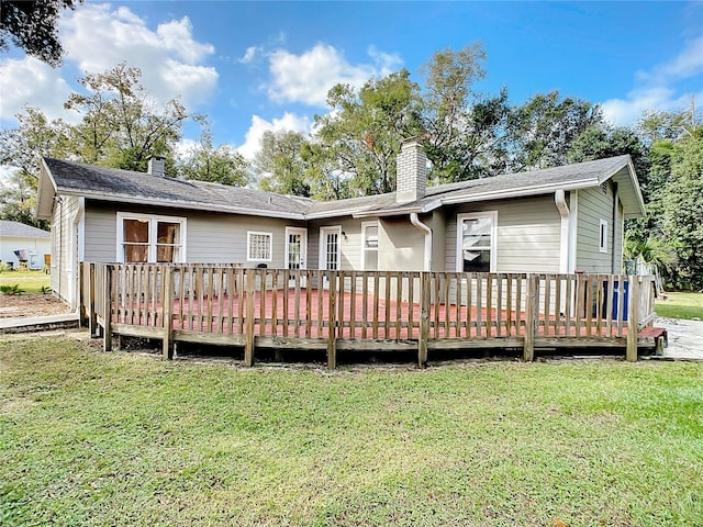 back of property with a deck and a yard