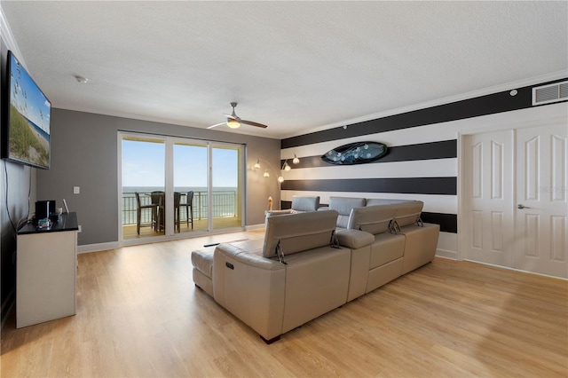 living room with ceiling fan, a textured ceiling, and light hardwood / wood-style floors