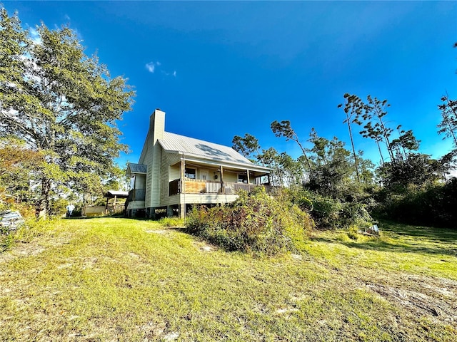 back of property with metal roof, a yard, and a chimney