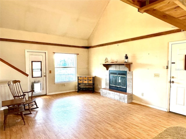 interior space with wood finished floors, beamed ceiling, a tile fireplace, and baseboards