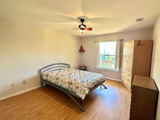 bedroom with baseboards, visible vents, ceiling fan, and wood finished floors