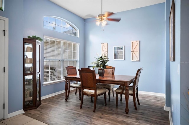 dining area featuring a high ceiling, wood-type flooring, and ceiling fan