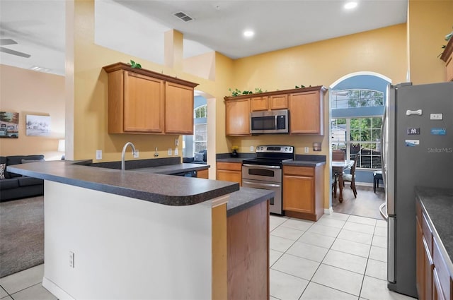 kitchen featuring kitchen peninsula, ceiling fan, stainless steel appliances, and light tile patterned floors