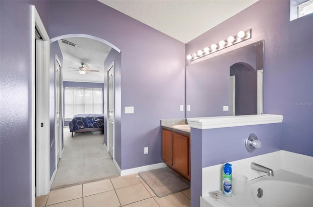 bathroom featuring a tub to relax in, a textured ceiling, ceiling fan, tile patterned floors, and vanity