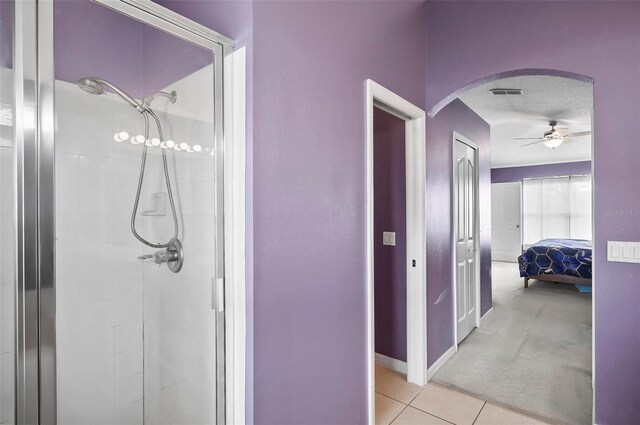 bathroom with tile patterned flooring, a tile shower, a textured ceiling, and ceiling fan