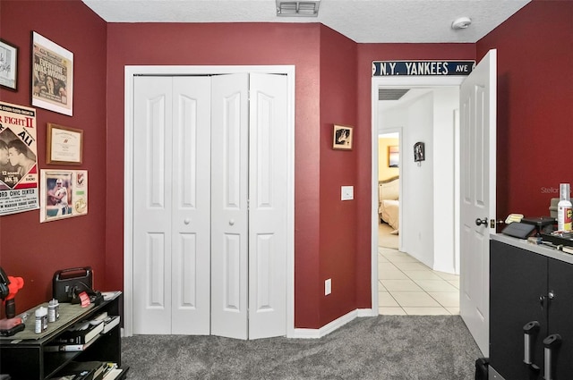 bedroom featuring a closet, light carpet, and a textured ceiling